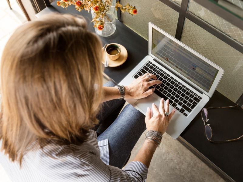 Hands using a laptop on a wooden desk