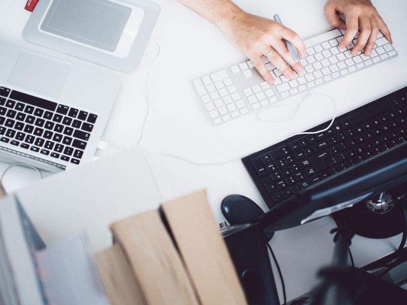 Hands at a keyboard beside a desktop device