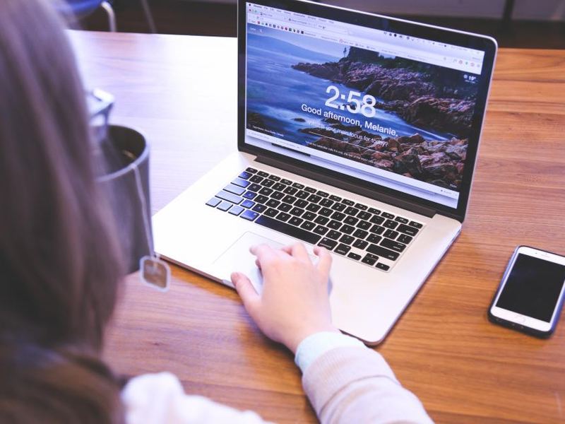 A laptop and phone on a desk beside printed notes