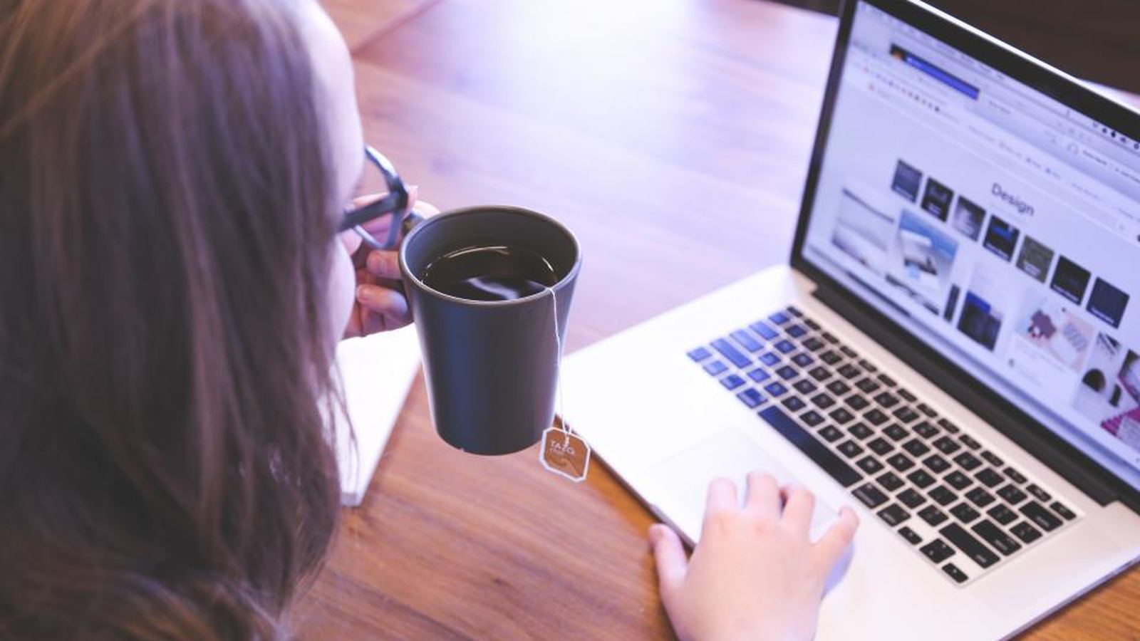 A laptop and coffee cup on a wooden desk