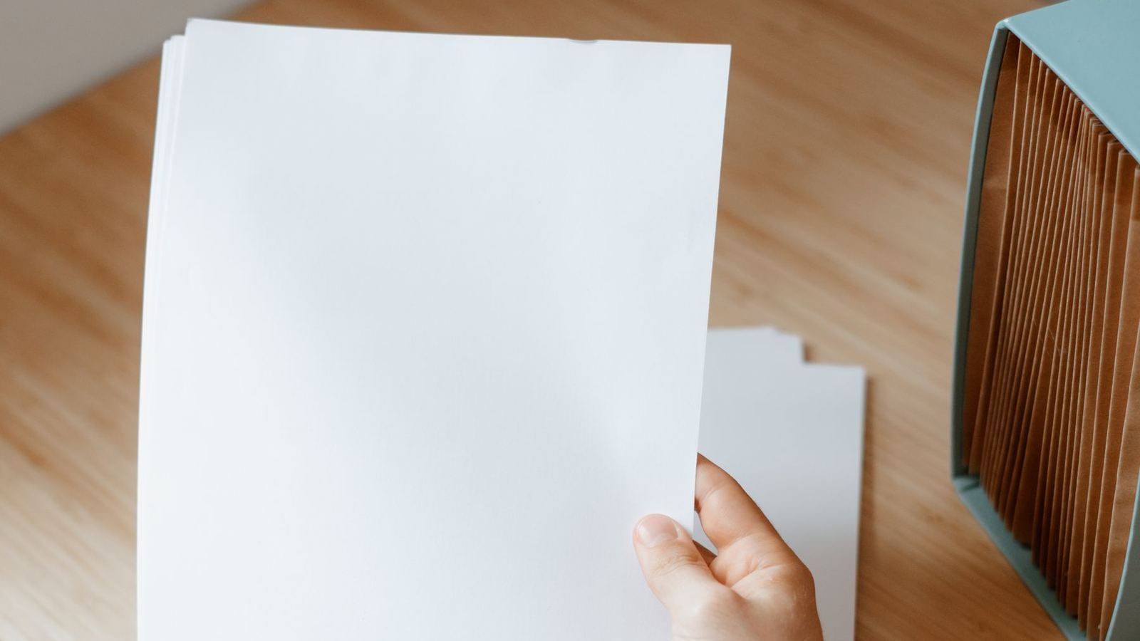 A freshly printed page held above a desk