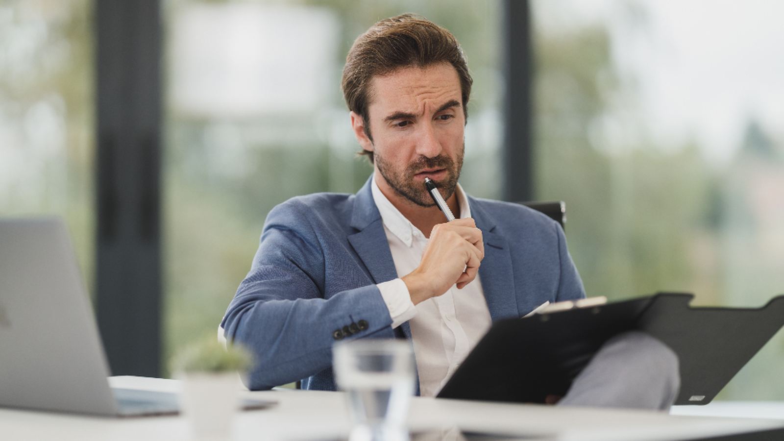 A person seated at a desk reviewing something on a tablet