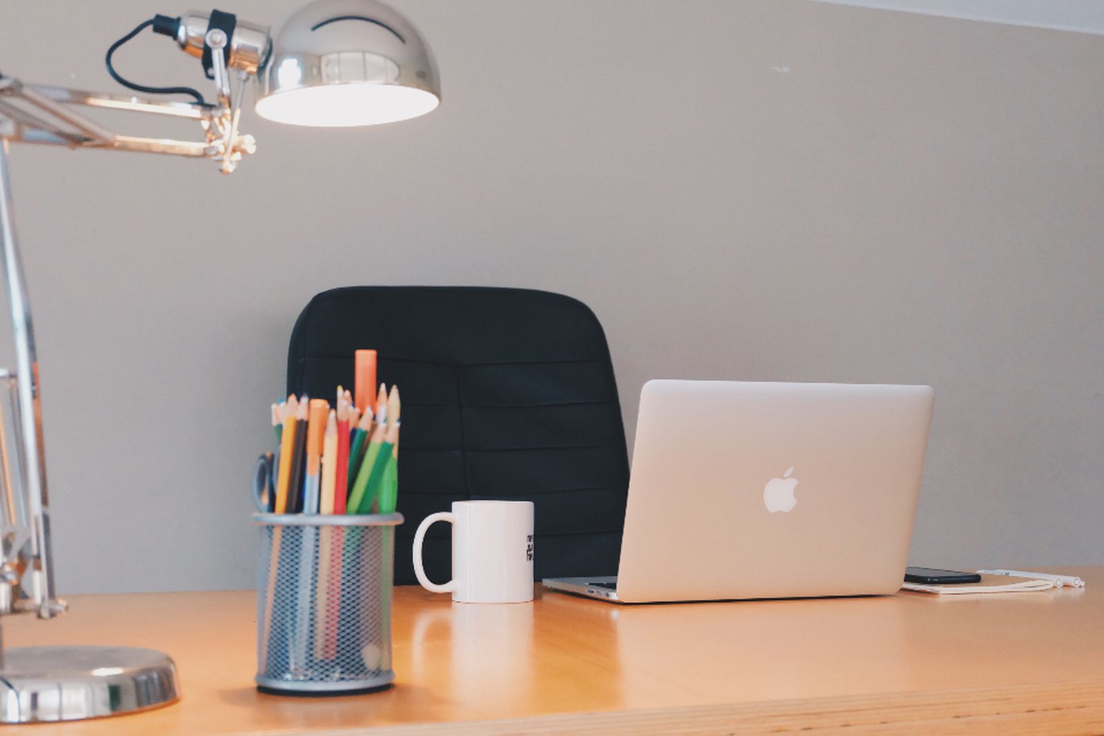 A desk with a laptop, pencils and stationery