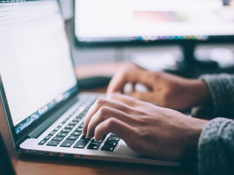 Hands typing on a laptop keyboard at a desk