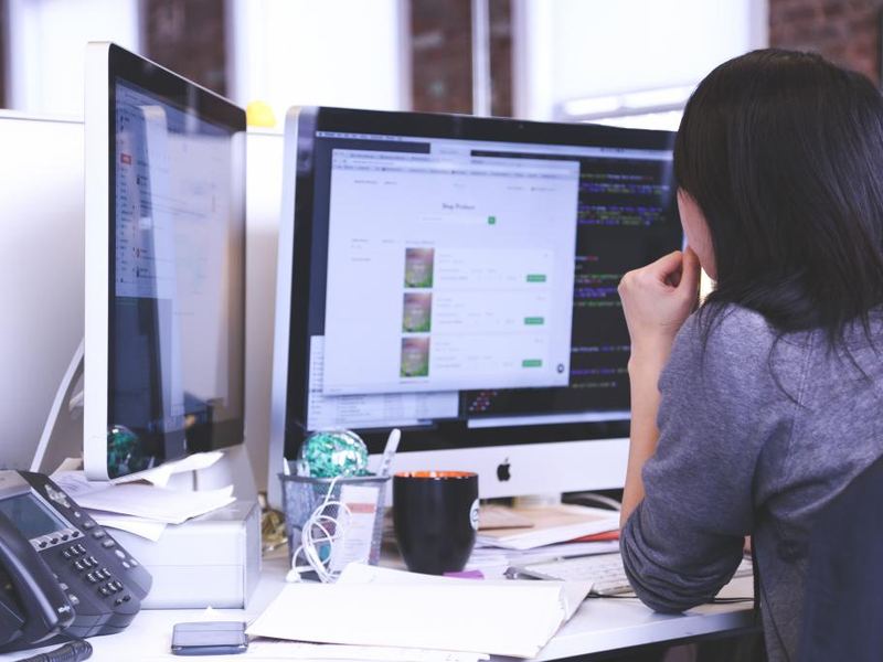 A person working at a desktop monitor, seen from behind