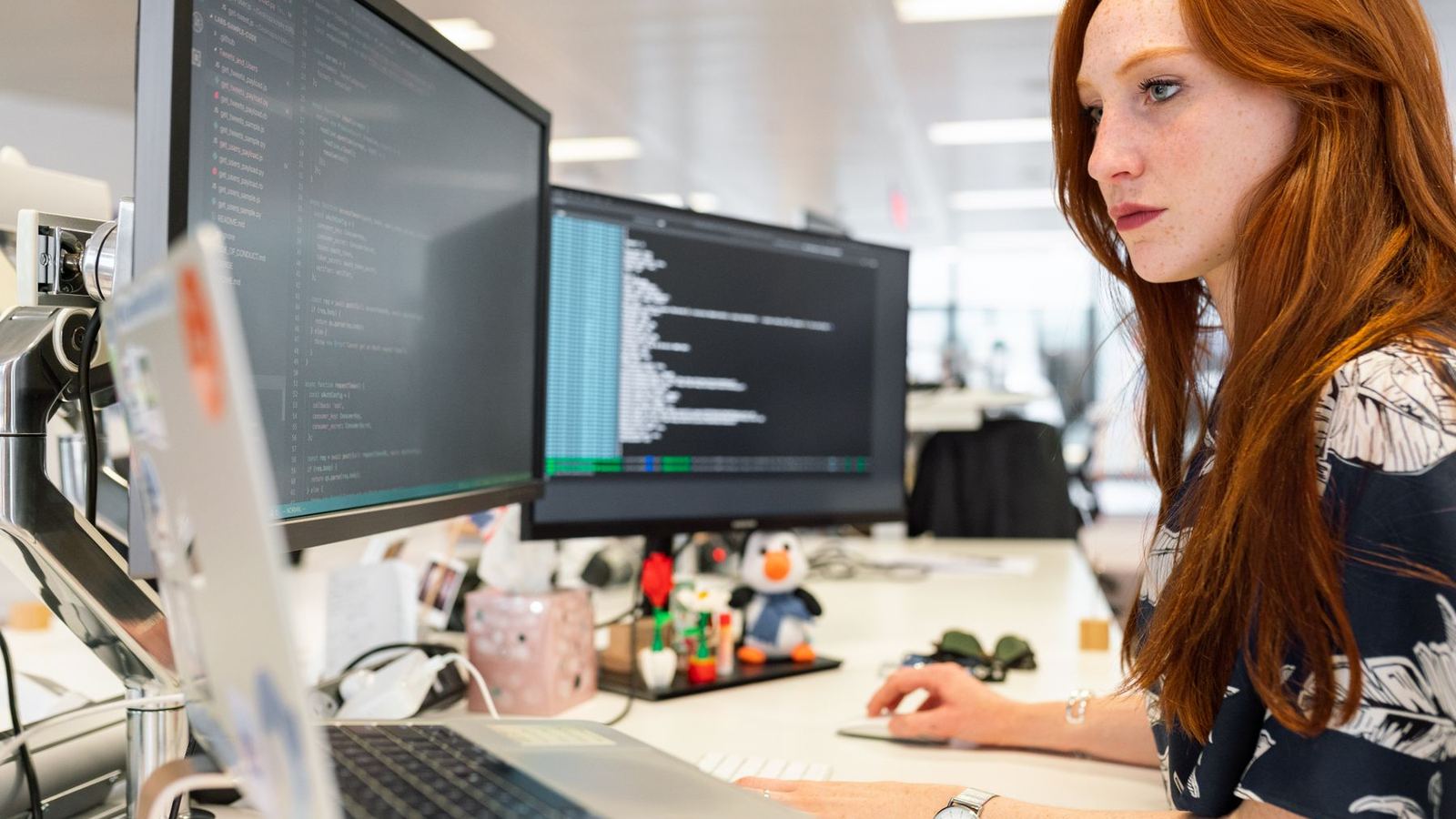 A person working at a dual-monitor desk in an office